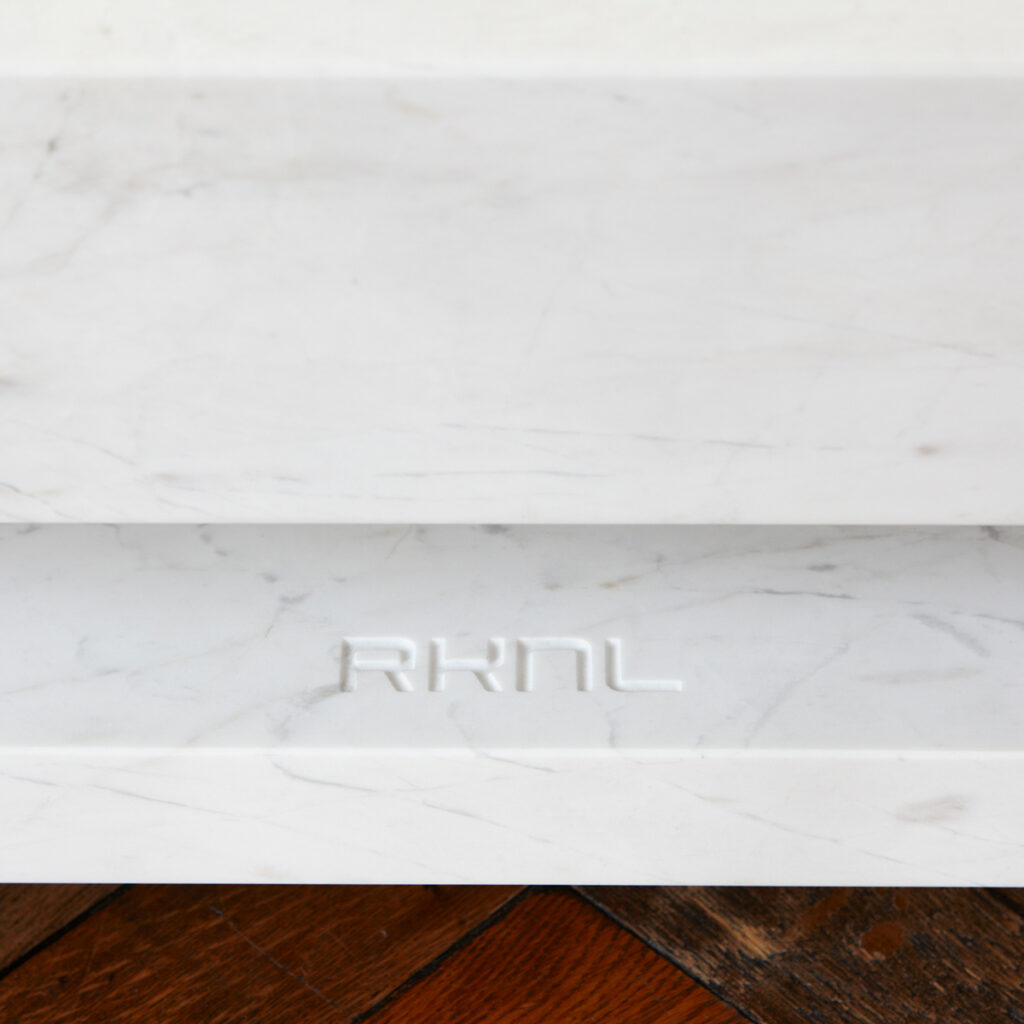 Logo RKNL gravé dans le plateau inférieur en marbre blanc veiné de gris